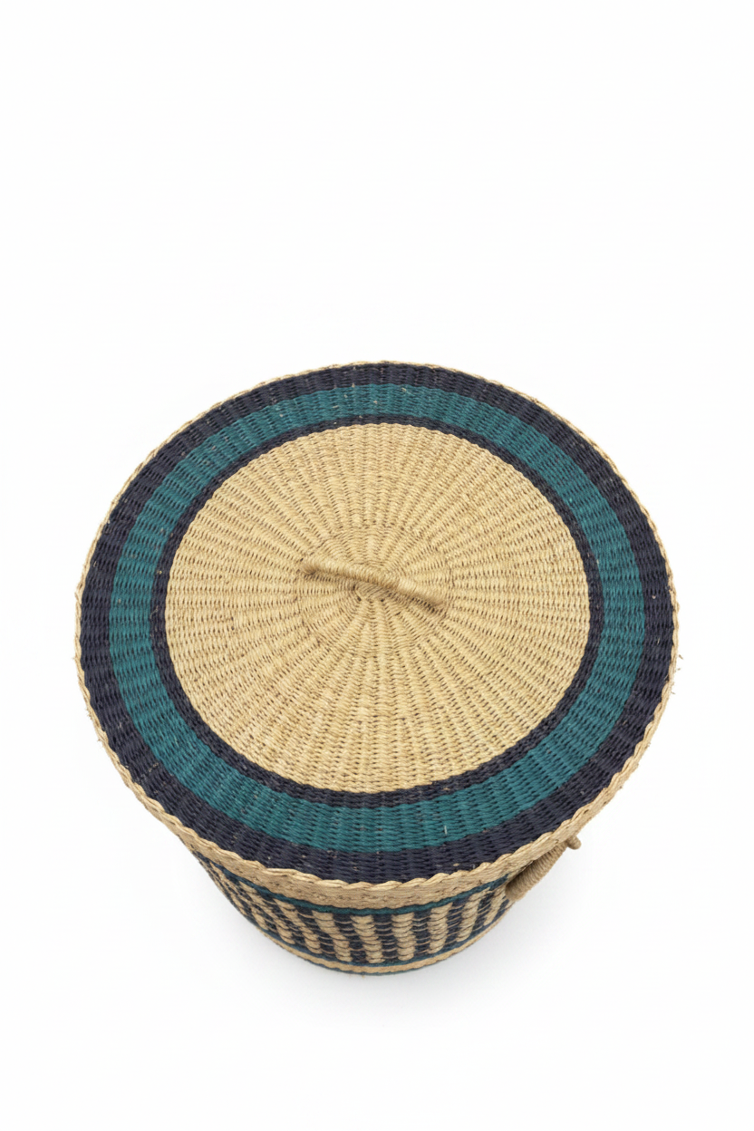 Panier artisanal africain vu de dessus, couvercle rond en paille tressée avec cercles concentriques teal et marine, centre naturel beige, anse centrale tressée packshot fond blanc