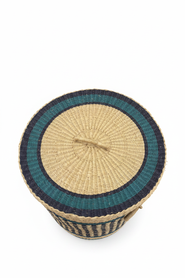 Panier artisanal africain vu de dessus, couvercle rond en paille tressée avec cercles concentriques teal et marine, centre naturel beige, anse centrale tressée packshot fond blanc