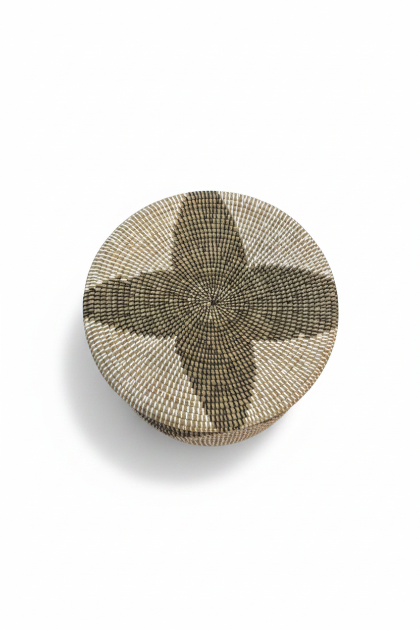 Vue du dessus du couvercle en jonc tressé, motif étoile à quatre pointes olive et crème, panier artisanal africain, fond blanc