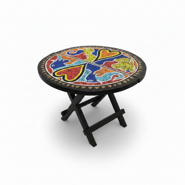 Table pliante en bois massif noir, plateau rond brodé de perles artisanales Ghana, motif animaux multicolores, pieds croisés repliables, vue trois quarts